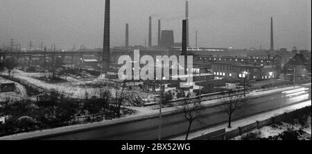 Sachsen-Anhalt / DDR Land / Winter / Dezember 1989 Winterabend in Bitterfeld, Braunkohlekombinat, Industriestandort, Ausfall-Straße // Stimmungen / Wirtschaft / Vertrauen / Industrie / Landschaft 1894 die Firma Chemische Fabrik Griesheim (Frankfurt am Main) In Bitterfeld wurde eine Fabrik zur Herstellung von chloriertem Kalk durch Elektrolyse errichtet. 1900 wurde das Verfahren auch zur Gewinnung von Magnesium und Aluminium eingesetzt, 1923 zog Griesheim komplett nach Bitterfeld. In der Nähe der Braunkohlebergwerke siedelten sich weitere Firmen an: Agfa baute eine Farb- und eine Folienfabrik. 1990 kam das Ende. Das VEB Chemiekombinat noch Stockfoto
