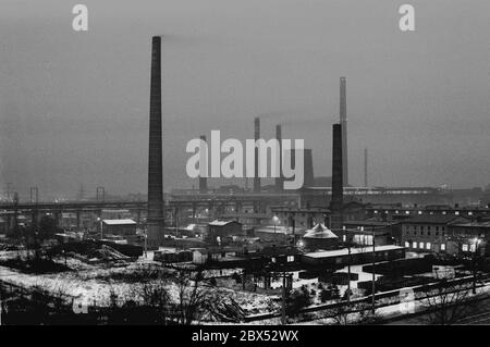 Sachsen-Anhalt / DDR Land / Winter / Dezember 1989 Winterabend in Bitterfeld, Braunkohlekombinat, Industriestandort, Ausfall-Straße // Stimmungen / Wirtschaft / Vertrauen / Industrie / Landschaft 1894 die Firma Chemische Fabrik Griesheim (Frankfurt am Main) In Bitterfeld wurde eine Fabrik zur Herstellung von chloriertem Kalk durch Elektrolyse errichtet. 1900 wurde das Verfahren auch zur Gewinnung von Magnesium und Aluminium eingesetzt, 1923 zog Griesheim komplett nach Bitterfeld. In der Nähe der Braunkohlebergwerke siedelten sich weitere Firmen an: Agfa baute eine Farb- und eine Folienfabrik. 1990 kam das Ende. Das VEB Chemiekombinat noch Stockfoto