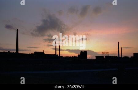 Sachsen-Anhalt / Industrie / DDR / 12/1991 Sonnenuntergang hinter dem Braunkohlekraftwerk in Bitterfeld // Energie / Umwelt / Industrielandschaft / Treuhand 1894 errichtete die Chemische Fabrik Griesheim (Frankfurt am Main) in Bitterfeld eine Fabrik zur Herstellung von chloriertem Kalk durch Elektrolyse. 1900 wurde das Verfahren auch zur Gewinnung von Magnesium und Aluminium eingesetzt, 1923 zog Griesheim komplett nach Bitterfeld. In der Nähe der Braunkohlebergwerke siedelten sich weitere Firmen an: Agfa baute eine Farb- und eine Folienfabrik. Ein großer VEB-Rohrleitungskombinat wurde ebenfalls gebaut. 1990 kam das Ende. Der VEB Stockfoto