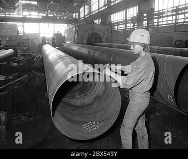 Ende der DDR / Sachsen-Anhalt / Metall-Industrie VEB Rohrleitungs-Kombinat in Bitterfeld, Werk Muldenstein, Dezember 1989: Das moderne Werk produzierte Großrohre und wurde später von Mannesmann übernommen. Frau an Gross-Rohren // Treuhand / Frauen / die Chemische Fabrik Griesheim (Frankfurt am Main) errichtete 1894 in Bitterfeld eine Fabrik zur Herstellung von chloriertem Kalk durch Elektrolyse. 1900 wurde das Verfahren auch zur Gewinnung von Magnesium und Aluminium eingesetzt, 1923 zog Griesheim komplett nach Bitterfeld. In der Nähe der Braunkohlebergwerke siedelten sich weitere Firmen an: Agfa baute eine Stockfoto