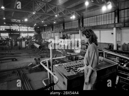 Ende der DDR / Sachsen-Anhalt / Metall-Industrie VEB Rohrleitungs-Kombinat in Bitterfeld, Werk Muldenstein, Dezember 1989: Das moderne Werk produzierte Großrohre und wurde später von Mannesmann übernommen. Frau am Maschinenstand // Treuhand / Frauen / die Firma Chemische Fabrik Griesheim (Frankfurt am Main) in Bitterfeld hat 1894 eine Fabrik zur Herstellung von chloriertem Kalk durch Elektrolyse errichtet. 1900 wurden auch Magnesium und Aluminium auf diesem Weg gewonnen, 1923 zog Griesheim komplett nach Bitterfeld. In der Nähe der Braunkohlebergwerke siedelten sich weitere Firmen an: Agfa baute Stockfoto