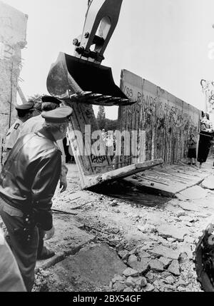 Berlin-Bezirk / Wedding / Mitte / 1990 Bernauer Strasse: Die Mauer fällt ! Am 12. Juni 1990 in Berlin-Wedding, Bernauer Straße. Als die Mauer 1961 gebaut wurde, sprangen die Menschen aus den Fenstern auf den Bürgersteig, um nach West-Berlin zu gelangen. Jetzt ist die Grenze weg. DDR-Grenzposten mit schwerem Gerät zum Abreißen der Mauer. // Berliner Mauer [automatisierte Übersetzung] Stockfoto