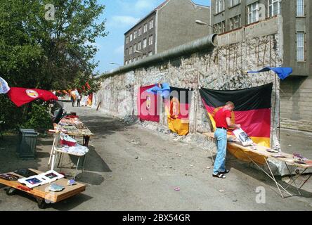 Berliner Bezirke / Kreuzberg / DDR / 11 /1989 Kreuzberg, Zimmerstraße: Troedler verkauft Mauerstücke als Souvenirs. Die Wand ist bereits sehr zerschlagen und voller Löcher, die von den Wandspechten geschnitten werden. Vor einer DDR-Flagge. Ende der DDR, Ende der Mauer // Berliner Mauer / Geschichte / Kommunismus / [automatisierte Übersetzung] Stockfoto