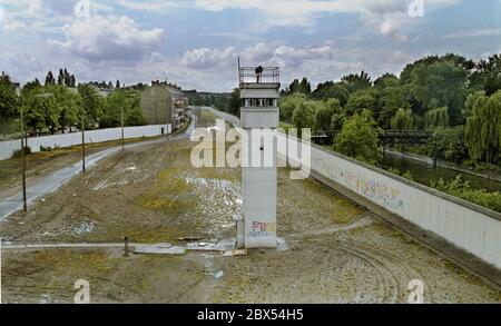 Berlin-Bezirk / DDR / 1990 Kreuzberg / Treptow: Die Wachtürme an der Berliner Mauer sind bereits verlassen, aber das Mauersystem ist noch immer deutlich sichtbar. Links der Zaun in Ost-Berlin, der Patrouillenweg für die Soldaten, der Hundelauf, der Wachturm mit Suchscheinwerfer, rechts die eigentliche Mauer nach Kreuzberg. // Grenze / Geschichte / Kommunismus [automatisierte Übersetzung] Stockfoto