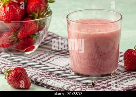 Erdbeer-Smoothie mit Milch im Glas auf grünem Hintergrund, gesunde Ernährung zum Frühstück und Snacks Stockfoto
