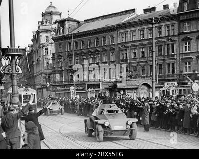 Deutscher Panzerspaehwagen Sdkfz. 221 (leichtes Panzeraufklärungsfahrzeug) durch die Mariahilfer Straße in Wien fahren. Auf der Straße befindet sich das Kaufhaus Leitner, ein Augenarzt und die Wiener Molkerei. Stockfoto