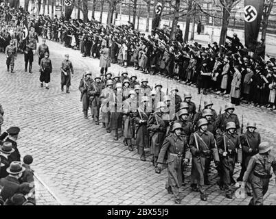 Soldaten der Armee und Mitglieder der SA marschieren anlässlich der Annexion Österreichs an das Deutsche Reich durch die Straßen Wiens. Die Soldaten (vorne) tragen Hakenkreuzbänder. Stockfoto