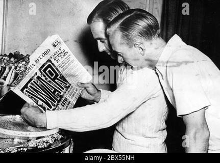 Adrian Quist (links), Tennisspieler im australischen Davis-Cup-Team, und Harry Hopman (rechts), Kapitän des Teams, lesen die Schlagzeilen über die deutsche Invasion in Polen und den Beginn des Krieges in einer amerikanischen Zeitung, dem "Philadelphia Record". Beide gehören dem Australian Army Reserve an und können damit rechnen, eingezogen zu werden, wenn Großbritannien in den Krieg eintritt. Stockfoto