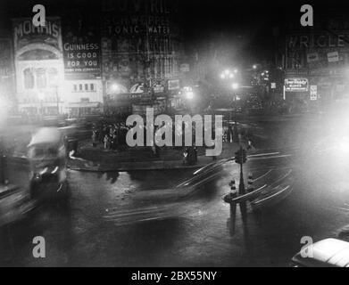 Picadilly Circus in London kurz vor der vollständigen Verdunkelung um 00:30 Uhr. Die Neonschilder und Verkehrsschilder sind bereits ausgeschaltet, nur die Straßenbeleuchtung funktioniert noch. Stockfoto