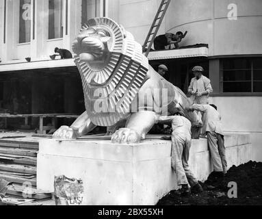 Arbeiter malen eine Löwenstatue, die die Treppe zum Pavillon der britischen Regierung flankiert. Dieses Gebäude ist Teil der Empire Exhibition, die von Mai bis Oktober 1938 im Bellahouston Park in Glasgow stattfand und am 3. Mai von König George VI feierlich eröffnet wurde. Stockfoto