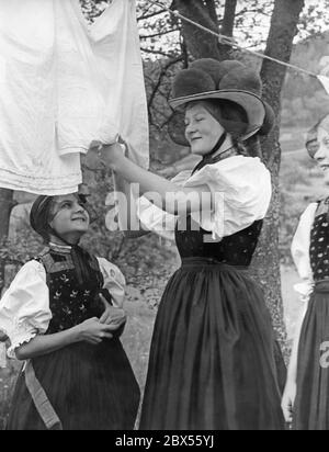 Drei Mädchen aus dem Gutachtental im Schwarzwald in Tracht beim Aufhängen ihrer Wäsche. Das Mädchen in der Mitte des Bildes trägt eine Bollenhütte. Das Bild wurde wahrscheinlich in den 1930er Jahren aufgenommen. Stockfoto