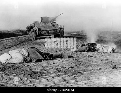 Die Leichen der sowjetischen Soldaten liegen in der Straße. Im Hintergrund befindet sich ein T-34 Panzer, der von einem deutschen Panzerabwehrkanone zerstört wurde. Während der Einkreisungsschlacht von Kholm verteidigte die Kampfgruppe Scherer die Stadt erfolgreich für 105 Tage. (Foto des Kriegsberichterstatters Richard Muck, der Anfang März in die Tasche flog). Stockfoto