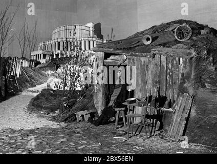 Blick auf die Ausstellung "das sowjetische Paradies" im Berliner Lustgarten: Ein Mann steht vor seiner armen Hütte. Daneben ist ein Bild einer Oper in Minsk, die die Kontraste propagandistisch symbolisieren soll. Stockfoto