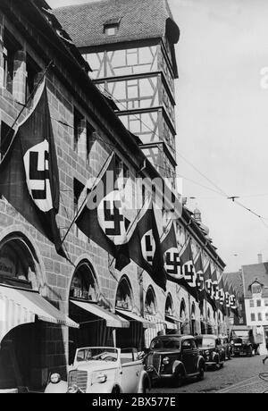 In Vorbereitung auf den Reichsparteitag ist die Mauthalle in der Lorenz-Altstadt von Nürnberg mit Hakenkreuzfans geschmückt. Im Vordergrund stehen mehrere Mercedes-Fahrzeuge. Stockfoto