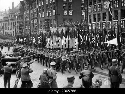 Adolf Hitler, der in seinem Mercedes steht, nimmt den Gruß der marschierenden SA-Fahnenträger auf dem Nürnberger Hauptmarkt, dem sogenannten Adolf-Hitler-Platz. Vor ihm von rechts: Rudolf Hess, Viktor Lutze, Adolf Huehnlein und andere. Im Vordergrund stehen mehrere Fotografen. Stockfoto