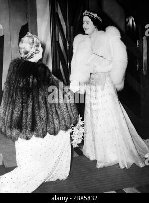 Königin Elizabeth wird bei einer Aufführung des französischen Nationaltheaters 'Comedie Francaise' im Savoy Hotel in London von Lady Bessborough, der Frau des Earl of Bessborough, der Vorsitzenden der Anglo-French Art and Travel Society, mit einem Blumenstrauß überreicht. Stockfoto