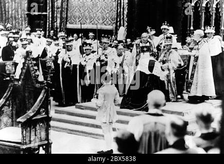 Nach seiner Krönung sitzt König Georg VI. Auf dem Thronstuhl mitten in der Kirche und erhält die Huldigung der Fürsten und Peers. Stockfoto