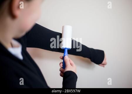 Hübsche junge Brünette Frau mit Roller für ihre schwarze Pullover, mit Roller für die Erfassung von Verunreinigungen Stockfoto