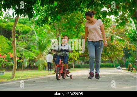 Flifure Porträt der asiatischen indonesischen Mutter und junge glückliche Sohn im Stadtpark Spaß zusammen das Kind lernen Fahrrad fahren und die Frau laufen Stockfoto