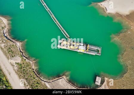 Vertikale Luftaufnahme eines Saugbaggers in einem Nassbergbaugebiet für Sand und Kies, mit angeschlossener Pipeline, um den Sand zu entfernen Stockfoto