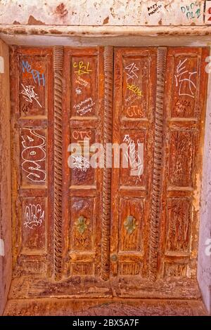 Graffiti an der wunderschön geschnitzten Tür in Venedig, Italien. Stockfoto