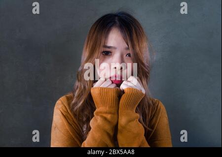 Junge verrückt verzweifelt und traurig asiatische koreanische Frau suchen depressiv und hilflos Gefühl Angst und Schmerz auf isolierten dunklen Hintergrund in Schmerz Gesicht expr Stockfoto