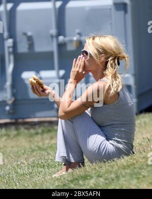 Pamela Anderson sitzt auf Gras und isst Burger in Malibu, CA Mai 2008 Stockfoto