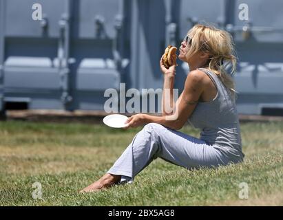 Pamela Anderson sitzt auf Gras und isst Burger in Malibu, CA Mai 2008 Stockfoto