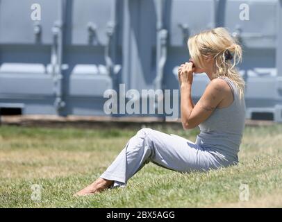 Pamela Anderson sitzt auf Gras und isst Burger in Malibu, CA Mai 2008 Stockfoto