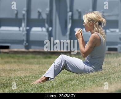 Pamela Anderson sitzt auf Gras und isst Burger in Malibu, CA Mai 2008 Stockfoto