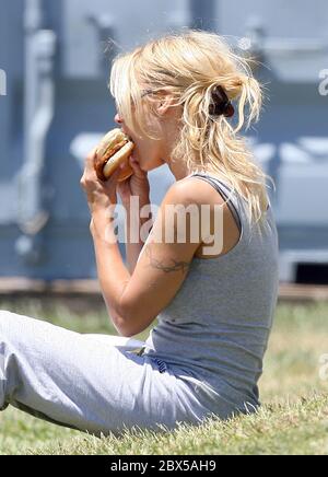 Pamela Anderson sitzt auf Gras und isst Burger in Malibu, CA Mai 2008 Stockfoto