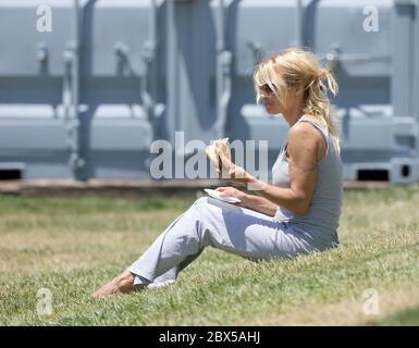 Pamela Anderson sitzt auf Gras und isst Burger in Malibu, CA Mai 2008 Stockfoto