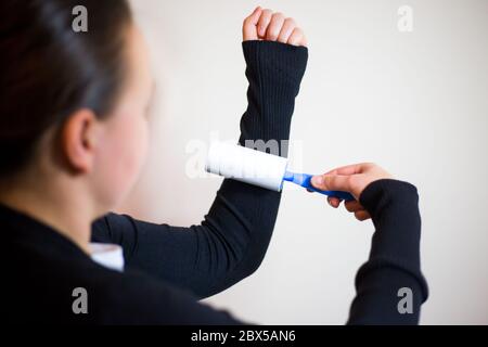 Hübsche junge Brünette Frau mit Roller für ihre schwarze Pullover, mit Roller für die Erfassung von Verunreinigungen Stockfoto