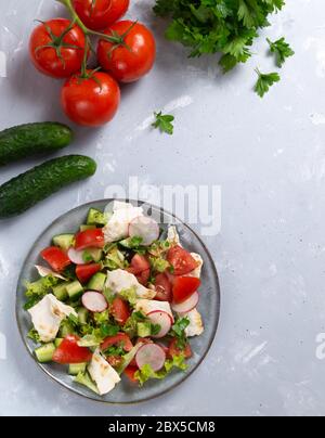 Fattoush Salat in einem grauen Teller mit Zutaten auf grauem Hintergrund. Draufsicht. Vertikale Ausrichtung Levantine Salat fattoush, die aus zubereitet wird Stockfoto