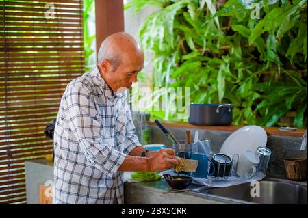 Lifestyle-Porträt von Senior glücklich und süß asiatischen japanischen pensionierten Mann Kochen zu Hause Küche allein ordentlich und ordentlich genießen die Zubereitung von Mahlzeiten in älteren Menschen Stockfoto