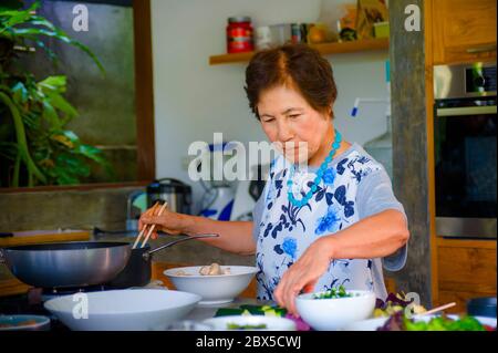 Lifestyle-Porträt von Senior glücklich und süß asiatisch Japanisch Rentner, Frau Kochen zu Hause Küche allein ordentlich und ordentlich genießen Zubereitung von Essen in elde Stockfoto