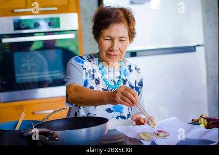 Lifestyle-Porträt von Senior glücklich und süß asiatisch Japanisch Rentner, Frau Kochen zu Hause Küche allein ordentlich und ordentlich genießen Zubereitung von Essen in elde Stockfoto