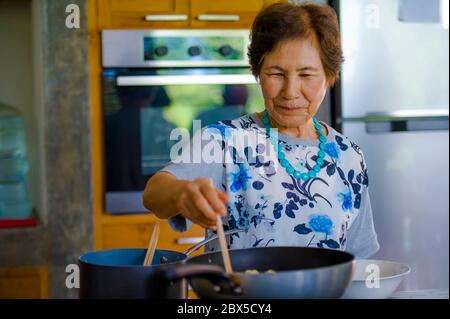Lifestyle-Porträt von Senior glücklich und süß asiatisch Japanisch Rentner, Frau Kochen zu Hause Küche allein ordentlich und ordentlich genießen Zubereitung von Essen in elde Stockfoto
