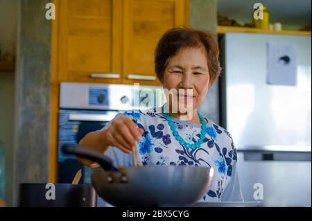 Lifestyle-Porträt von Senior glücklich und süß asiatisch Japanisch Rentner, Frau Kochen zu Hause Küche allein ordentlich und ordentlich genießen Zubereitung von Essen in elde Stockfoto