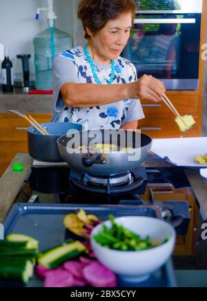 Lifestyle-Porträt von Senior glücklich und süß asiatisch Japanisch Rentner, Frau Kochen zu Hause Küche allein ordentlich und ordentlich genießen Zubereitung von Essen in elde Stockfoto