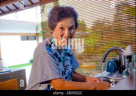 Lifestyle-Porträt von Senior glücklich und süß asiatischen japanischen Ruhestand, Frau Kochen zu Hause Küche allein ordentlich und ordentlich Waschen der Gerichte lächelnd chee Stockfoto