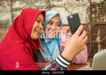 Muslimische Teenager Schüler Freundinnen Selfie. Glücklich und hübsch asiatisch indonesische Mädchen in traditionellen islamischen Hijab Kopf Schal unter Selfie zusammen hav Stockfoto