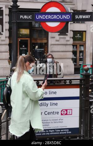 Personen mit Gesichtsmasken passieren den Eingang zur U-Bahn am Bahnhof Piccadilly im Zentrum von London, nachdem angekündigt wurde, dass das Tragen einer Gesichtsbedeckung ab Juni 15 für Passagiere mit öffentlichen Verkehrsmitteln in England obligatorisch sein wird. Stockfoto
