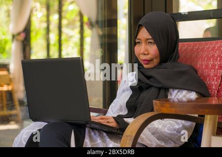Lifestyle-Porträt des mittleren Alters asiatische indonesische muslimische Frau in traditionellen Hijab Kopf Schal Arbeit entspannt zu Hause laufen Online-Geschäft in inte Stockfoto