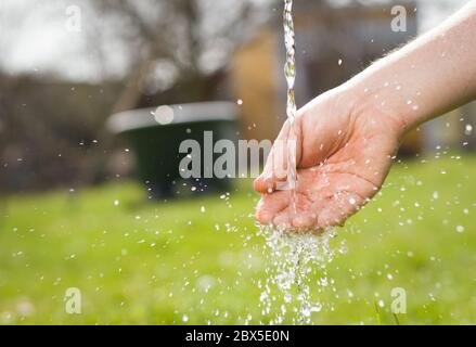 Eine alte Hand aktiver Senior, die seine schmutzige Hand nach der Gartenarbeit an seinem riesigen botanischen Garten, harte Arbeit, Gartenarbeit, wäscht Stockfoto