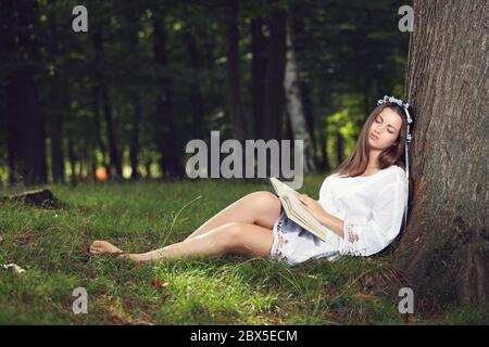 Schöne Frau, wie eine Nymphe gekleidet, die friedlich im Wald schläft Stockfoto