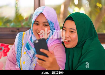 Muslimische Teenager Schüler Freundinnen Selfie. Glücklich und hübsch asiatisch indonesische Mädchen in traditionellen islamischen Hijab Kopf Schal unter Selfie zusammen hav Stockfoto