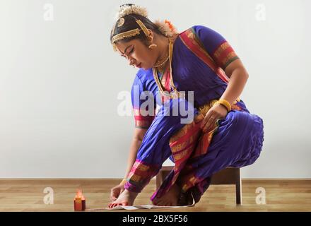 Bharatnatyam Tänzerin sitzt und Anwendung alta auf ihre Füße. Stockfoto