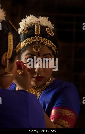 Bharatnatyam Tänzerin schaut sich selbst im Spiegel an und wendet Kajal in ihre Augen an. Stockfoto