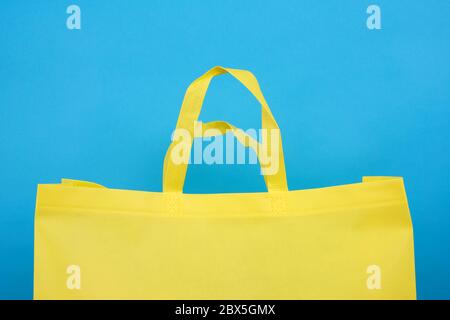 Wiederverwendbare gelbe Viskose Tasche auf blauem Hintergrund, Kunststoff Abfallvermeidung Konzept Stockfoto